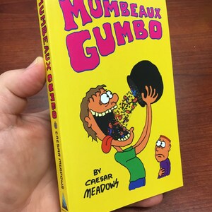 May include: A yellow book cover with the title "Mumbeaux Gumbo" in pink letters. The cover features a cartoon illustration of a person with a large mouth eating a pot of gumbo. The text "By Caesar Meadows" is printed below the illustration.