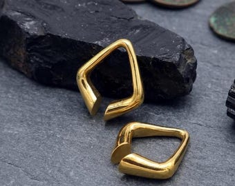 May include: Two gold-toned ear weights with a smooth, polished finish and a distinct geometric, open-ended square shape. These metallic pieces feature rounded edges and a continuous, solid construction, presenting a reflective surface.
