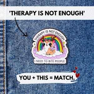 Puede incluir: Un pin de esmalte colorido con un ciervo de dibujos animados con una corona floral, sobre un fondo de arcoíris y nubes. El pin incluye el texto "THERAPY IS NOT ENOUGH" y "I NEED TO BITE PEOPLE". También está presente el texto "YOU + THIS = MATCH".
