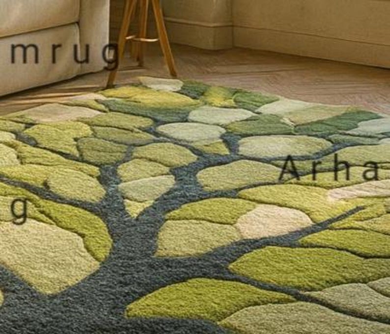May include: A green and beige area rug with a tree design. The rug features a dark gray trunk and branches, with leaf-shaped patterns in various shades of green and beige. The rug is on a wooden floor.