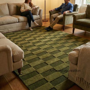 May include: A green and olive-colored area rug with a geometric pattern. The rug is rectangular and covers a wooden floor. The text "Arhaamrugcreation" is visible on the rug.