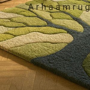May include: A rectangular area rug with a tree-like design. The rug features a pattern of green, light green, and beige leaf shapes, with a dark gray trunk. The text "Arhaamrug" is visible in the upper right corner.