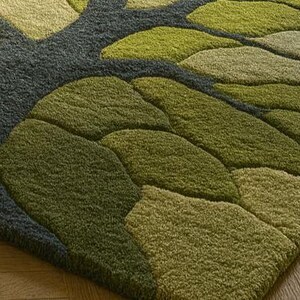 May include: A green and gray area rug with a leaf design. The rug features a pattern of overlapping leaf shapes in various shades of green, with a gray background. The rug is made of a soft, textured material.