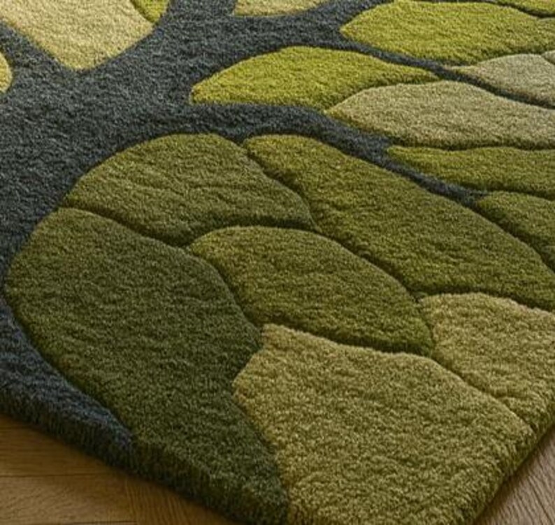 May include: A green and gray area rug with a leaf design. The rug features a pattern of overlapping leaf shapes in various shades of green, with a gray background. The rug is made of a soft, textured material.