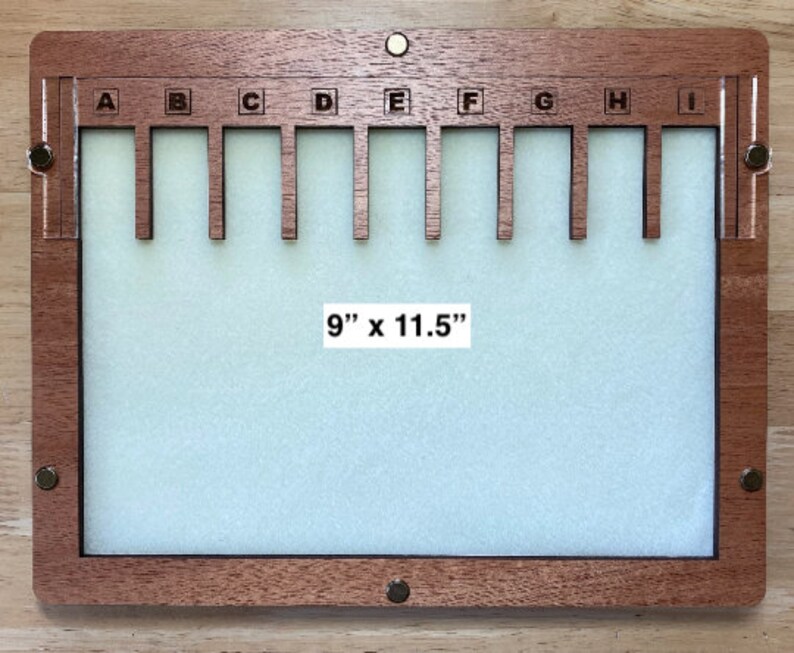 Puede incluir: Un tablero de exhibici&oacute;n de madera con un interior verde claro y un marco marr&oacute;n oscuro. El tablero tiene nueve ranuras etiquetadas de la A a la I. El texto "9" x 11.5" (22,86 cm x 29,21 cm) es visible.