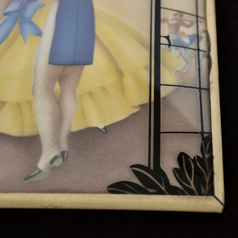K&ouml;nnte beinhalten: Eine gerahmte Vintage-Illustration eines Paares, das in einem Ballsaal tanzt. Die Frau tr&auml;gt ein gelbes Kleid und der Mann tr&auml;gt eine blaue Jacke. Der Rahmen hat ein schwarzes und goldenes Design mit einem schwarzen und wei&szlig;en Blumenmuster.
