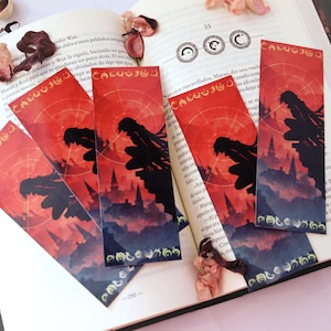 May include: Four rectangular bookmarks featuring a vibrant red and dark silhouette illustration of a character crouching on a rooftop overlooking a city. The design includes circular geometric patterns and decorative script at the top and bottom edges.
