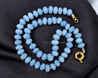 Op de afbeelding: Een lichtblauwe kralenketting met een gouden sluiting. De ketting bestaat uit kleine, afgeronde kralen geregen op een lichtblauw koord. De tekst "TEST GEMS" is zichtbaar op de achtergrond.