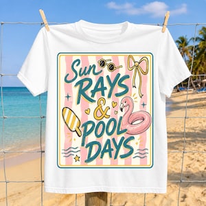Könnte beinhalten: Weißes T-Shirt mit einem farbenfrohen Grafikdesign. Das Design zeigt den Text "Sun Rays & Pool Days" mit Illustrationen von Sonnenbrillen, einer Schleife, einem Eis am Stiel und einem Flamingo-Schwimmring. Das T-Shirt hängt an einer Wäscheleine.