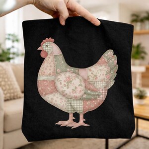 May include: Black tote bag with a patchwork chicken design. The chicken is made from various fabric patterns, including floral, gingham, and solid colours in pink, green, and cream. The bag is held up by a hand.