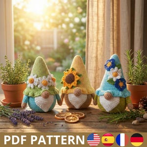May include: Three handmade crochet gnomes with conical hats and white beards are displayed on a wooden surface. The gnomes have different colored hats: green with daisies, yellow with a sunflower, and blue with flowers. The image includes the text "PDF PATTERN".