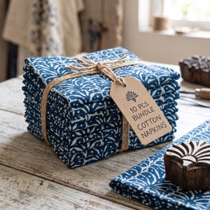 May include: A stack of ten folded cotton napkins featuring a blue and white botanical block print pattern. The bundle is tied with natural jute twine and includes a brown paper tag printed with the text 10 PCS BUNDLE COTTON NAPKINS.