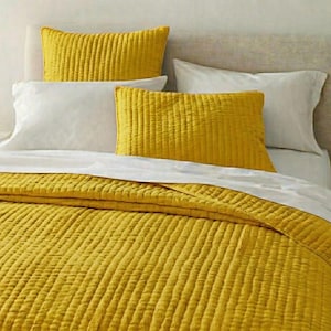 May include: A bed featuring a yellow quilted duvet cover and matching pillowcases. White sheets and pillows complement the yellow. The headboard is a neutral tone. The bedding has a textured, ribbed pattern.