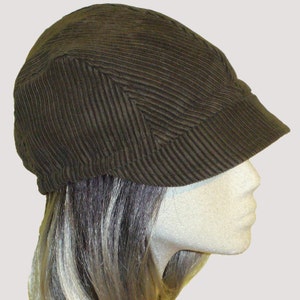 Puede incluir: Una gorra de estilo newsboy de pana marr&oacute;n con una visera ligeramente curvada. La gorra est&aacute; hecha de un tejido suave y texturizado.