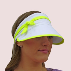 May include: White visor with a neon yellow trim and a bow on the headband.