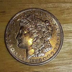 Pu&ograve; includere: Una moneta d'argento americana Peace Dollar con l'anno 1921 inciso sul fondo. La moneta presenta un profilo di una donna con i capelli fluenti e le parole "LIBERTY" e "E PLURIBUS UNUM" in alto.