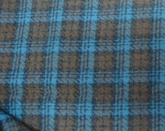 May include: A woven fabric featuring a plaid pattern with intersecting lines in shades of bright blue and dark brown. The textile displays a consistent grid design with a soft, slightly fuzzy texture visible across the surface of the material.