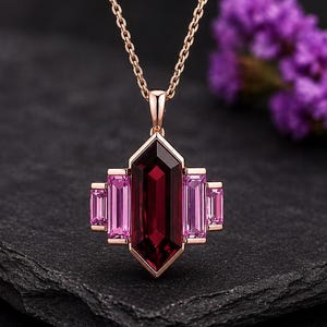 Puede incluir: Collar de oro rosa con un colgante con una gran gema rectangular de color rojo oscuro en el centro, flanqueada por cuatro gemas rosas rectangulares más pequeñas. El colgante cuelga de una delicada cadena.