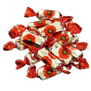 May include: A pile of individually wrapped candies. Each candy wrapper is red and twisted at the ends. The candy wrappers have a white background with yellow polka dots and a red poppy flower design.