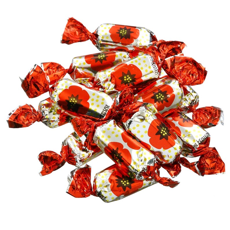 May include: A pile of individually wrapped candies. Each candy wrapper is red and twisted at the ends. The candy wrappers have a white background with yellow polka dots and a red poppy flower design.