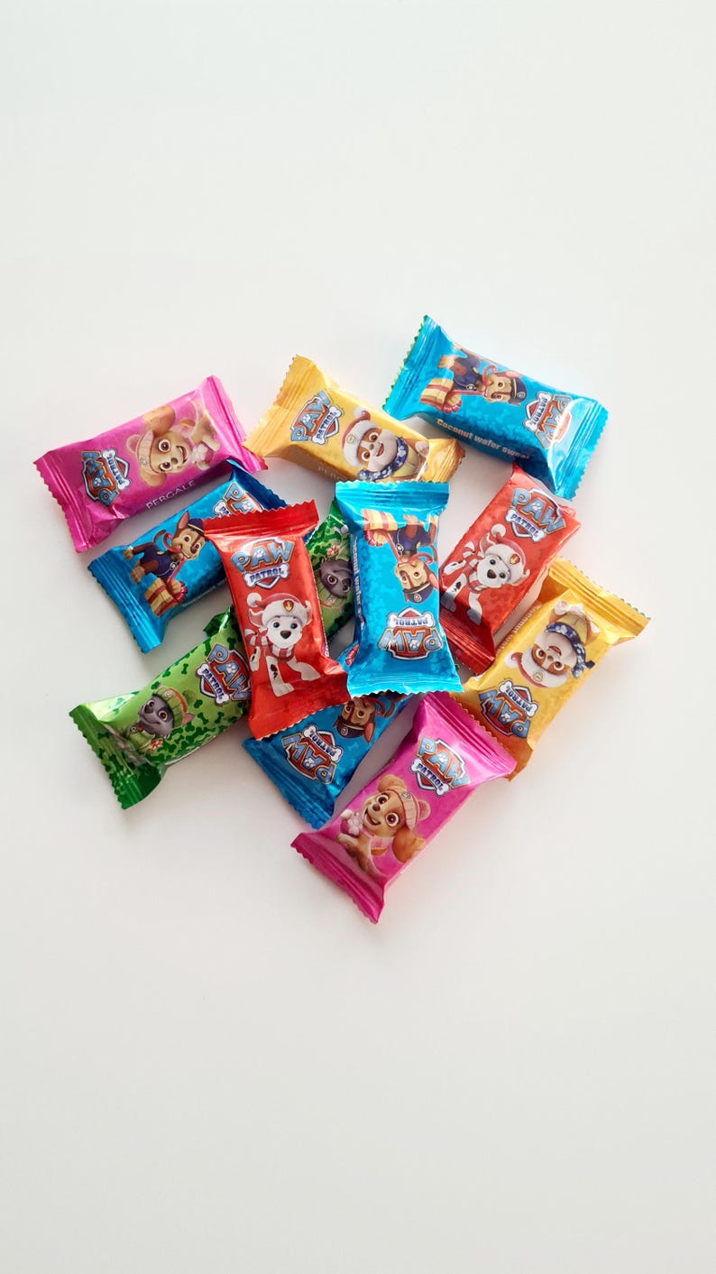 May include: A collection of individually wrapped candy bars featuring characters from the Paw Patrol animated series. The wrappers are various colors, including pink, blue, yellow, green, and red, with the Paw Patrol logo.