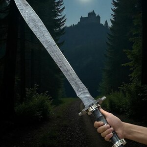 May include: A long, silver sword with a patterned blade is held against a backdrop of a forest path leading to a castle under a full moon. The sword has a dark handle with gold-colored accents.