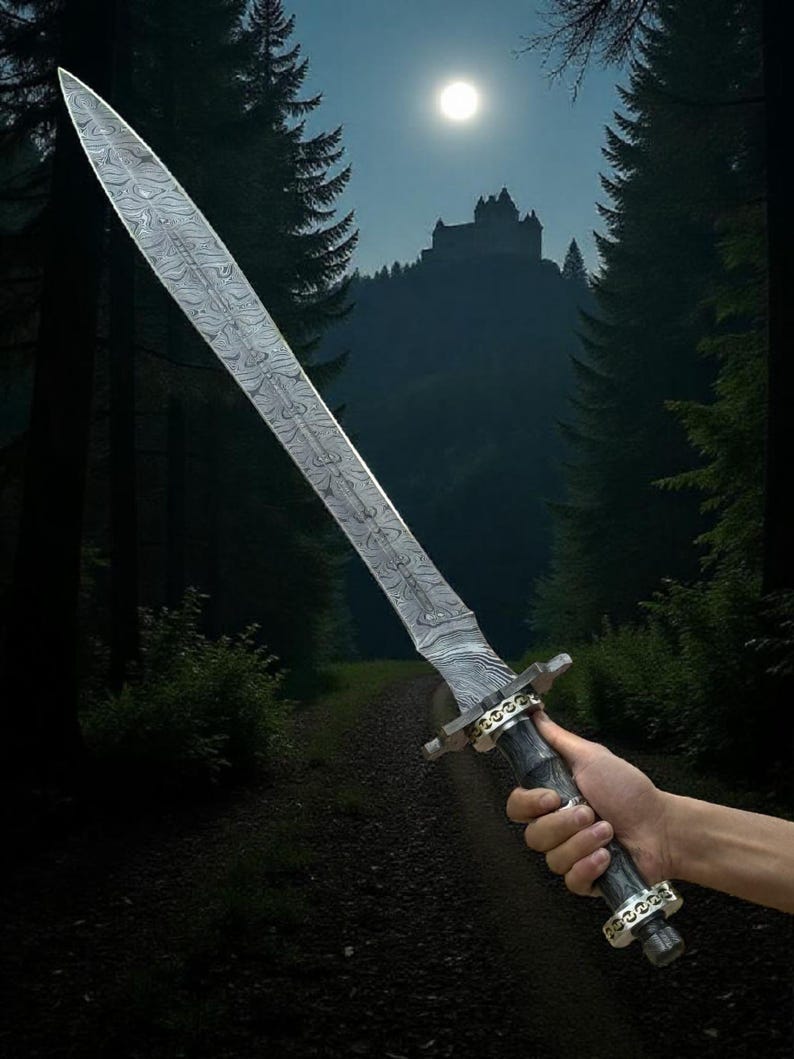 May include: A long, silver sword with a patterned blade is held against a backdrop of a forest path leading to a castle under a full moon. The sword has a dark handle with gold-colored accents.