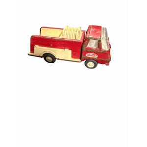 May include: Vintage red and cream-colored toy fire truck. The truck features a ladder rack and a cab with a clear windshield. The wheels are black with white rims. The truck has the word "Tonka" on the side.