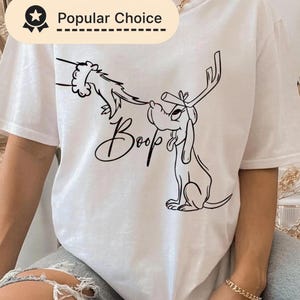Adorable motif de chien de Noël avec un petit nez retroussé, un chiot avec des bois de renne et une main de Père Noël : dessin au trait amusant pour t-shirts et cadeaux. Style croquis festif pour la sublimation.