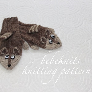 Op de afbeelding: Een paar bruine en beige gebreide wanten met een wasbeergezichtontwerp. De wanten hebben zwarte ogen en een bruine neus. De tekst "bebeknits knitting pattern" staat onder de wanten.