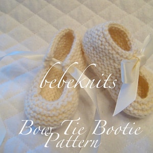 May include: A pair of white knitted baby booties with a white satin bow on each. The booties are tied with a white satin ribbon. The text "bebeknits Bow Tie Bootie Pattern" is written below the booties.