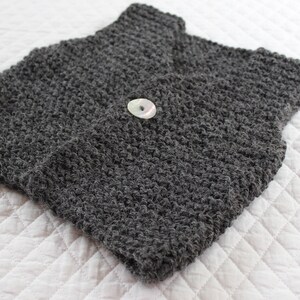 May include: A grey knitted waistcoat with a single white button.