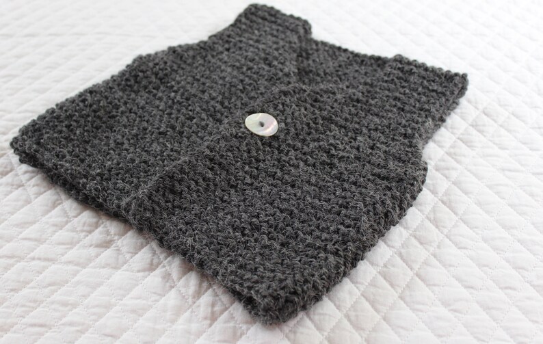 May include: A grey knitted waistcoat with a single white button.