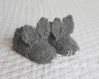 May include: A pair of gray knitted baby booties with ear-like flaps. The booties are made with a soft, fuzzy yarn and have a pink lining. The text "Bebeknits knitting pattern" is visible in the bottom right corner of the image.