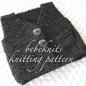 Pode incluir: Um colete de malha cinzento escuro para beb&eacute; com dois bot&otilde;es pretos. O colete est&aacute; dobrado e tem uma etiqueta que diz "bebeknits knitting pattern".