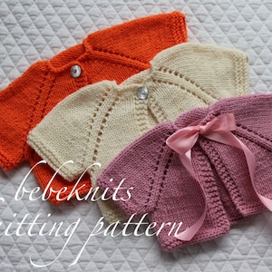 Puede incluir: Tres cárdigans de punto para bebé en naranja, crema y rosa. Los cárdigans están dispuestos sobre una tela acolchada blanca. El texto "bebeknits knitting pattern" es visible en la esquina inferior izquierda de la imagen.
