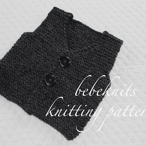 Pode incluir: Um colete de malha cinzento com dois bot&otilde;es pretos. O colete est&aacute; sobre uma superf&iacute;cie branca. O texto "bebeknits knitting pattern" &eacute; vis&iacute;vel no canto inferior direito da imagem.