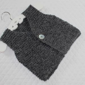 May include: A grey knitted cowl neck scarf with a single button fastening.
