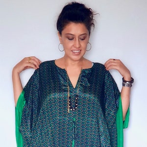 May include: A green and blue patterned kaftan with a green trim. The kaftan has a V-neck and a drawstring waist.