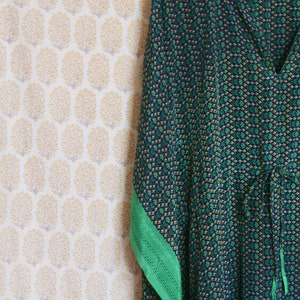 May include: A blue and green patterned kaftan with a green trim. The kaftan has a V-neck and a tie at the waist.