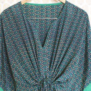 May include: A blue and green patterned kaftan with a V-neck and a gathered waist.