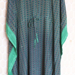 May include: A blue and green patterned kaftan with a green trim. The kaftan has a V-neck and a tie at the waist.