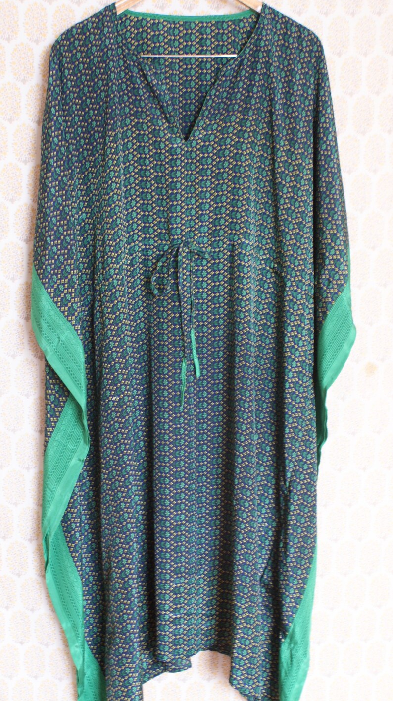 May include: A blue and green patterned kaftan with a green trim. The kaftan has a V-neck and a tie at the waist.