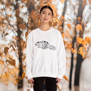 Op de afbeelding: Witte sweatshirt met een zwart-wit beverontwerp. De beverillustratie is gevuld met bloemen en geometrische patronen. De sweatshirt is een crew neck stijl en wordt door een persoon gedragen.
