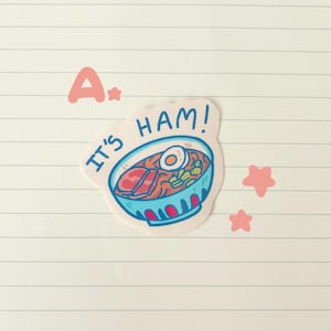 May include: A sticker featuring a cartoon bowl of ramen with a slice of ham and a boiled egg. The text "IT'S HAM!" is written above the bowl. Pink stars and the letter "A" are also present.