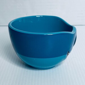 K&ouml;nnte beinhalten: Eine zweifarbige Keramikschale mit gl&auml;nzender Oberfl&auml;che, bestehend aus einem dunkelblauen oberen Bereich und einem helleren t&uuml;rkisfarbenen unteren Bereich. Die Schale hat eine runde Form mit einer Vertiefung am rechten Rand des Gef&auml;&szlig;es.