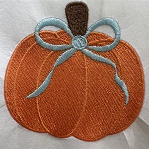 Puede incluir: Calabaza naranja bordada con un lazo azul claro y un tallo marr&oacute;n. La calabaza es un dise&ntilde;o con tem&aacute;tica oto&ntilde;al, perfecto para manualidades y decoraciones de temporada. El bordado es detallado y texturizado.