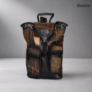 May include: A patchwork leather backpack with a black base and accents. The bag features two front zippered pockets and a top handle. The patchwork design incorporates various shades of brown, tan, and burgundy leather. The bag has a buckle closure and gold-toned hardware.