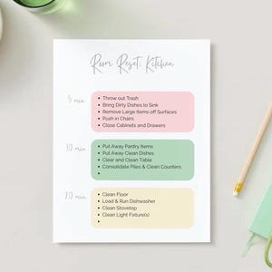 Może przedstawiać: Biała kartka z napisem "Room Reset: Kitchen" i listą kontrolną sprzątania. Lista zawiera zadania na 5, 10 i 20 minut, takie jak wyrzucanie śmieci, mycie naczyń i czyszczenie podłogi. Widoczny jest również ołówek, klucze i mały notatnik.