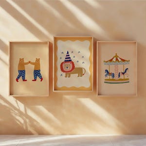 Puede incluir: Tres impresiones artísticas enmarcadas con ilustraciones caprichosas. Una muestra dos osos tomados de la mano, otra un león con un gorro de fiesta y la última un carrusel con caballos. Las impresiones están en marcos de madera.